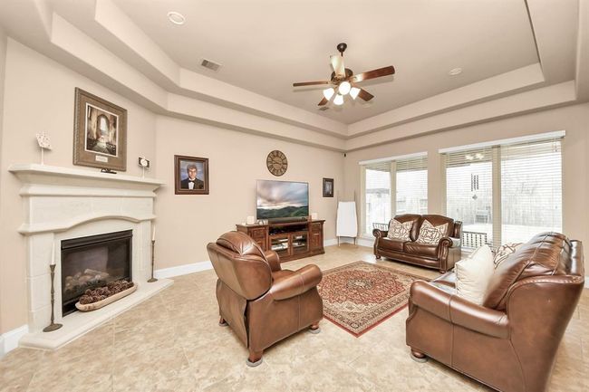 Large living room with a wall of windows, trayed ceilings, and gaslog fireplace. | Image 7