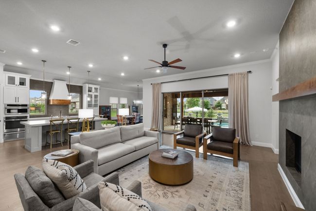 Oversized living room with ceiling fan, light wood floors, crown molding, and a plethora of natural light | Image 10