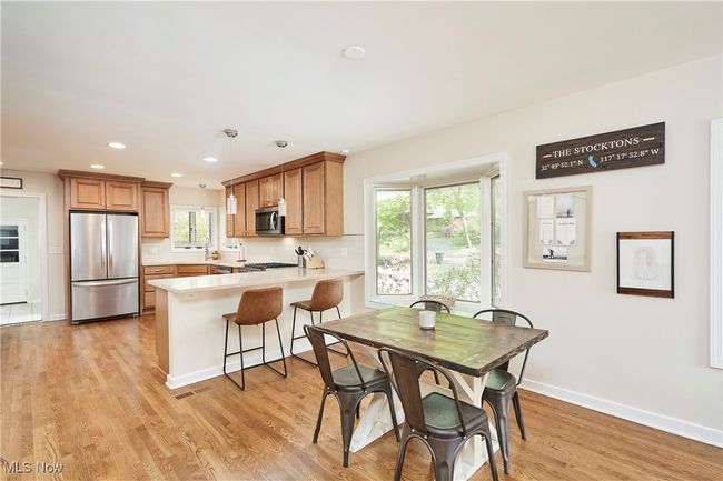 Kitchen with appliances with stainless steel finishes, a peninsula, light countertops, light wood finished floors, and baseboards | Image 11