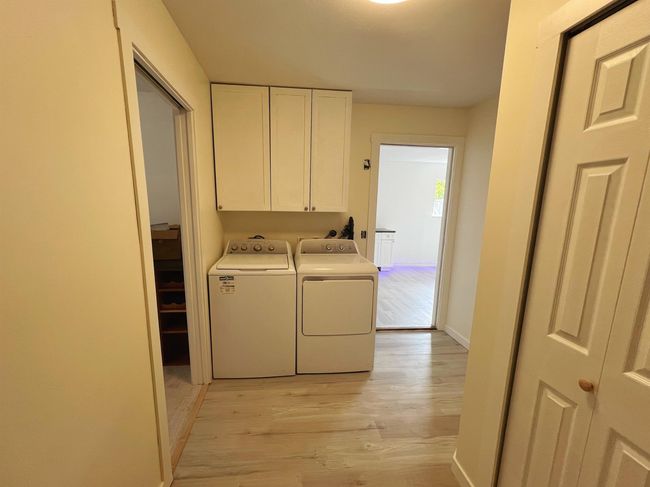 Laundry room featuring washing machine and clothes dryer, cabinet space, and light wood-style floors | Image 11