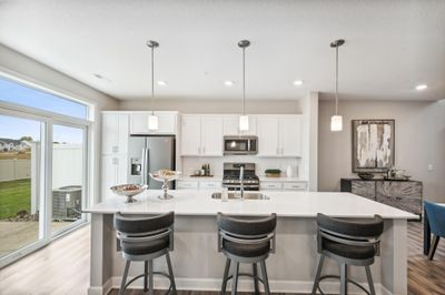 (Photo of decorated model, actual home's finishes will vary) Enjoy plenty of seating at the kitchen island and dining area adjacent to the kitchen. Perfect for entertaining or having a family meal together. | Image 3