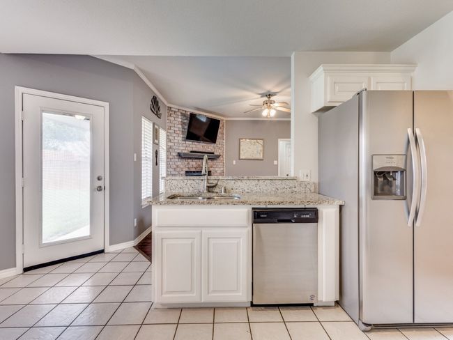 Kitchen featuring appliances with stainless steel finishes, a sink, white cabinets, light tile patterned floors, and ornamental molding | Image 11