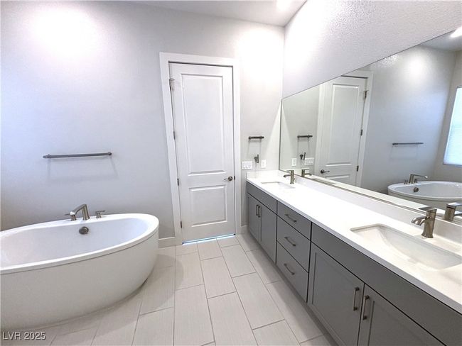 Full bath featuring double vanity, a soaking tub, tile patterned floors, and a sink | Image 26