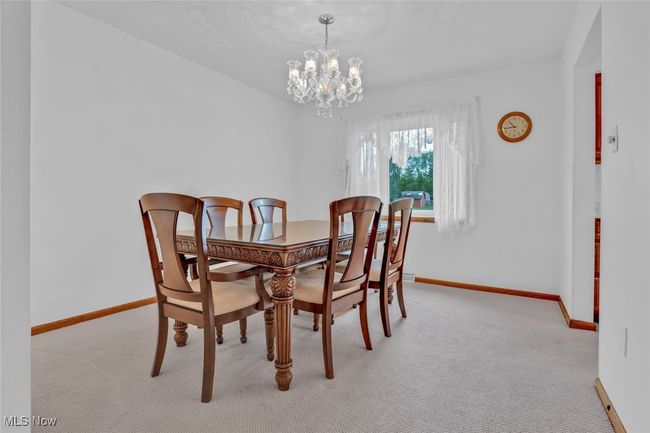 Dining room featuring light colored carpet, a chandelier, and baseboards | Image 11