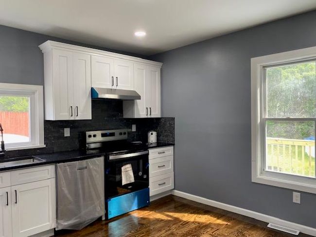Kitchen featuring dishwasher, electric range oven, under cabinet range hood, dark countertops, and tasteful backsplash | Image 14