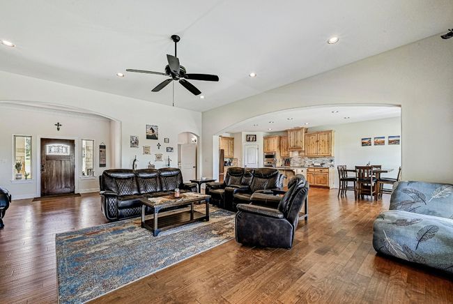 Living room with arched walkways, dark wood-style flooring, ceiling fan, and recessed lighting | Image 5