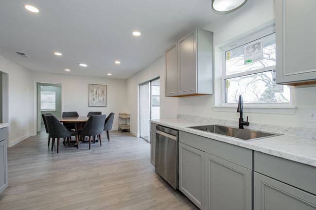 Kitchen with gray cabinets, stainless steel dishwasher, recessed lighting, light wood finished floors, and light stone countertops | Image 12