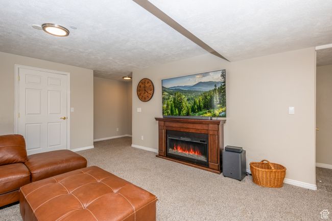 Living room featuring carpet, a glass covered fireplace, baseboards, and a textured ceiling | Image 26