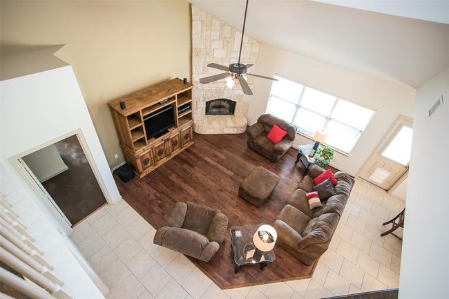 Living room with wood finished floors, a stone fireplace, a ceiling fan, and vaulted ceiling. | Image 18