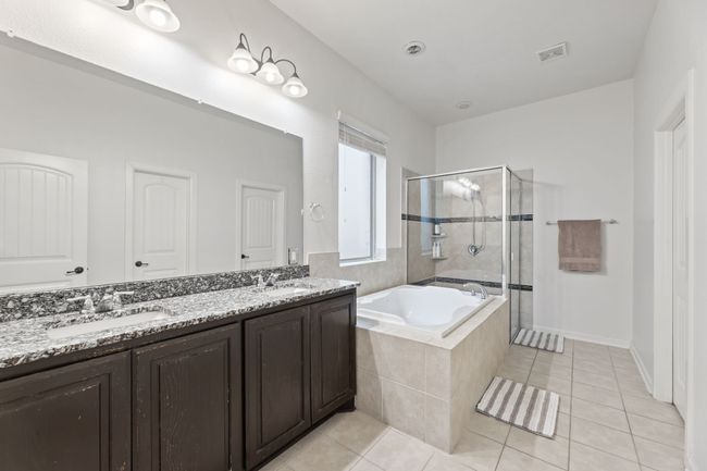 Bathroom featuring a stall shower, a bath, double vanity, tile patterned flooring, and baseboards | Image 19