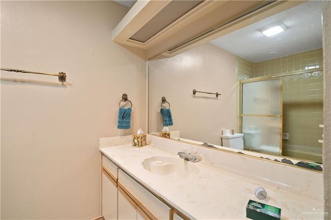 Bathroom with vanity, a textured ceiling, and combined bath / shower with glass door | Image 15