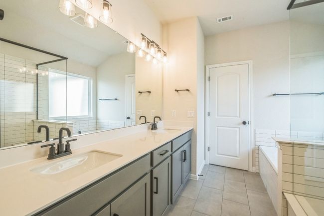 Full bath with double vanity, a bath, tile patterned flooring, lofted ceiling, and tiled shower | Image 8