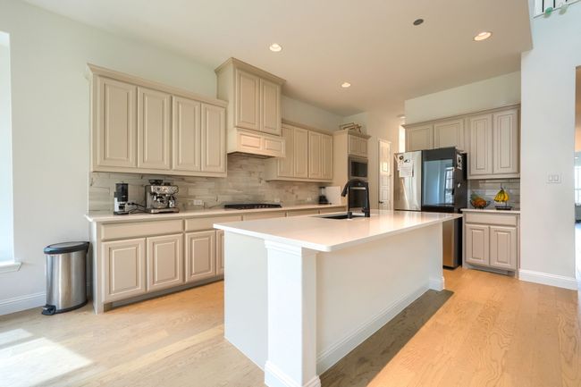Kitchen featuring tasteful backsplash, cream cabinetry, light wood-style flooring, and a sink | Image 12