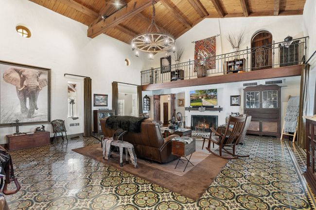Living area featuring high vaulted ceiling, wood ceiling, beamed ceiling, and a lit fireplace | Image 15