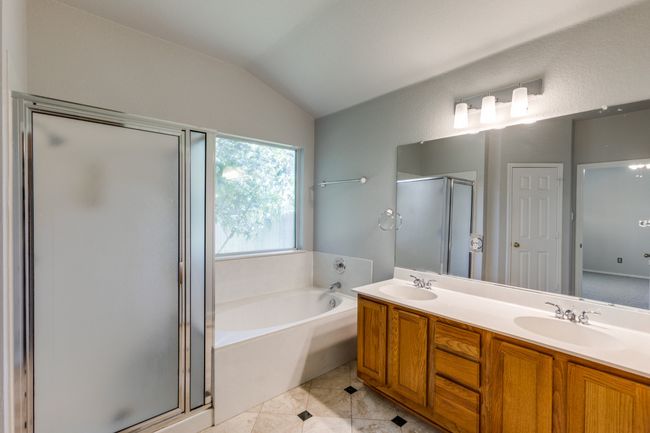 Master Full bath featuring a stall shower, a garden tub, double vanity, lofted ceiling, and tile patterned floors | Image 31