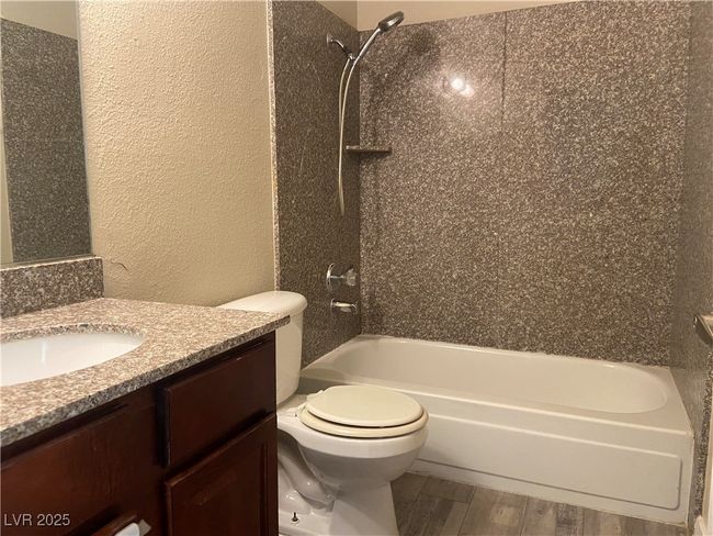 Full bath with vanity, washtub / shower combination, wood finished floors, toilet, and a textured wall | Image 16
