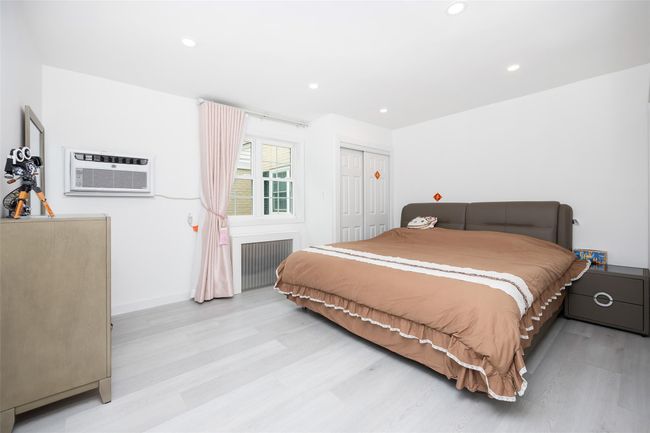 Bedroom with radiator, a wall mounted AC, light wood-style floors, recessed lighting, and a closet | Image 14