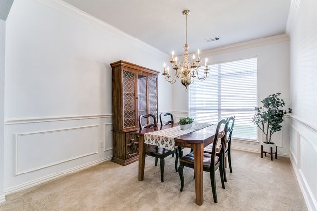 Dining area features a chandelier, crown moulding, a wainscoting panels. | Image 8