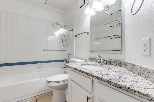 Bathroom featuring vanity, shower / bathtub combination, a textured wall, and tile patterned flooring | Image 13