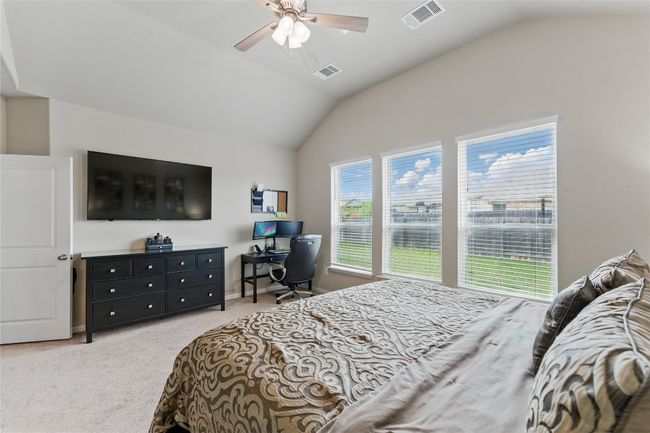Bedroom with carpet flooring, ceiling fan, lofted ceiling, and visible vents | Image 20