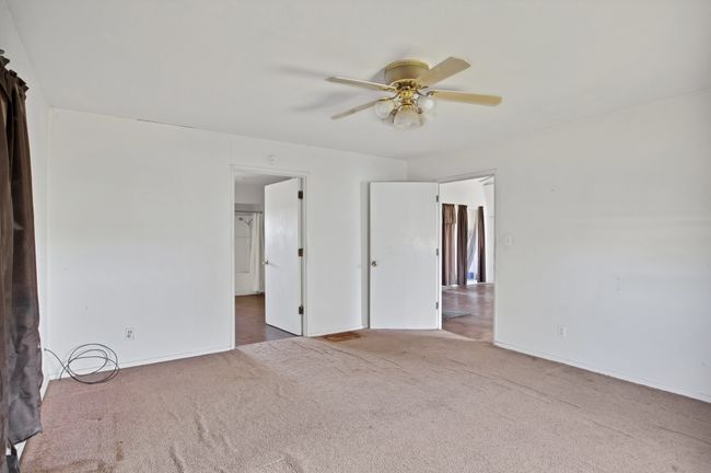 Carpeted empty room with a ceiling fan and baseboards | Image 21