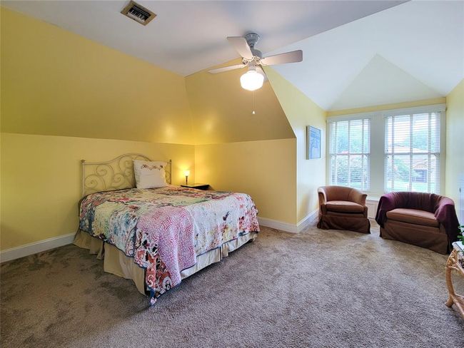 Spacious upstairs bedroom with cozy sitting area and abundant natural light from expansive windows. | Image 25