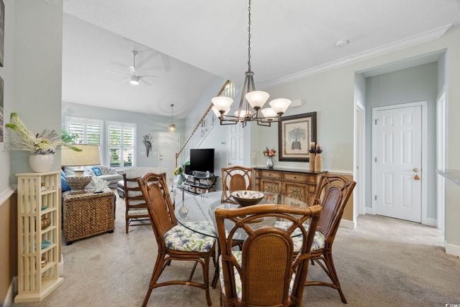 Dining space featuring light carpet, a chandelier, lofted ceiling, a ceiling fan, and ornamental molding | Image 10
