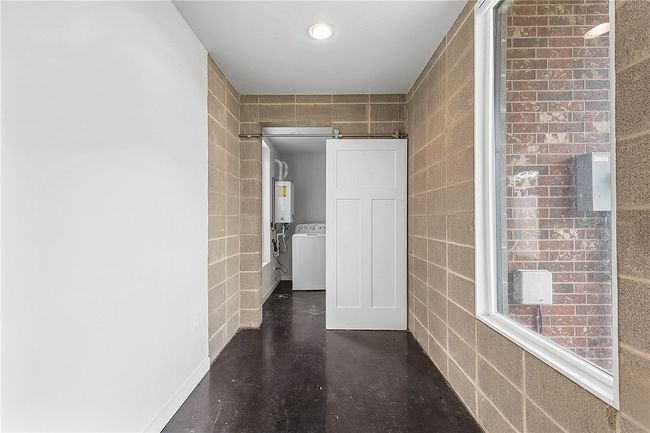 Corridor with water heater, tile walls, recessed lighting, independent washer and dryer, and concrete flooring | Image 32