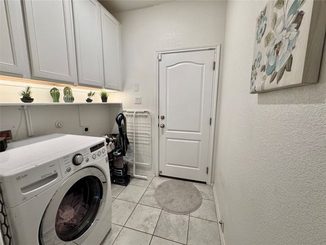 Laundry room with washer / clothes dryer, cabinet space, light tile patterned floors, and a textured wall | Image 21