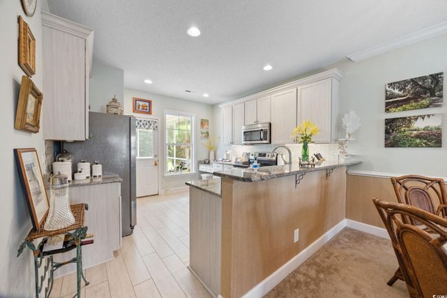 Kitchen featuring a peninsula, stone counters, appliances with stainless steel finishes, backsplash, and recessed lighting | Image 21