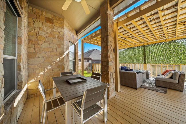 Experience serene outdoor living on the spacious covered patio, featuring a pergola and seating area ideal for entertaining. Enjoy the blend of wood decking and stone accents, creating a welcoming extension of the home that invites relaxation in a private setting. | Image 33