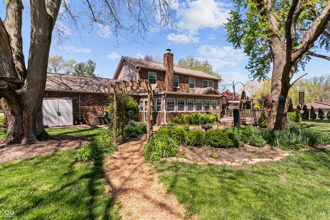 back of house with a pergola, a chimney, a lawn, a wooden deck, and brick siding | Image 42
