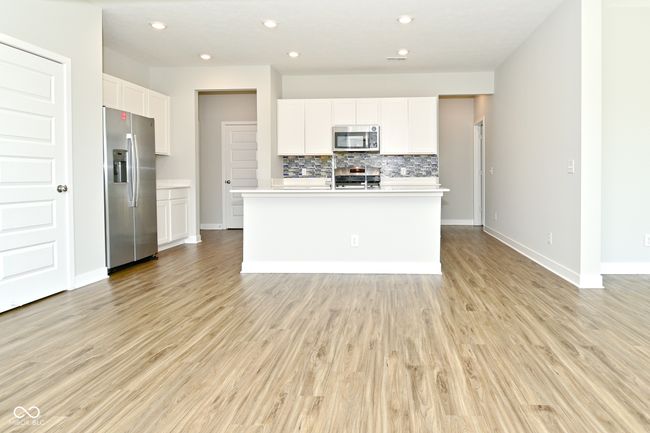 kitchen featuring light countertops, white cabinetry, light wood-style floors, decorative backsplash, and stainless steel appliances | Image 7