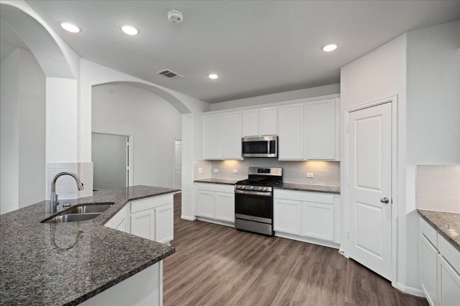 Kitchen with appliances with stainless steel finishes, a sink, arched walkways, tasteful backsplash, and dark stone counters | Image 12