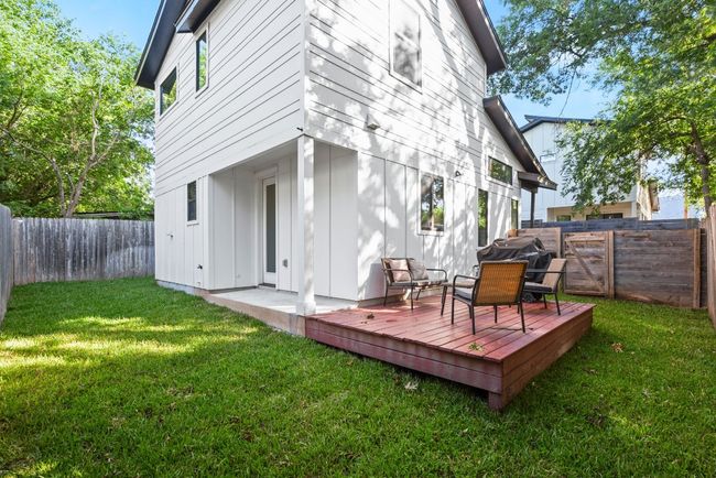 Back of property with board and batten siding, a wooden deck, and a fenced backyard | Image 7