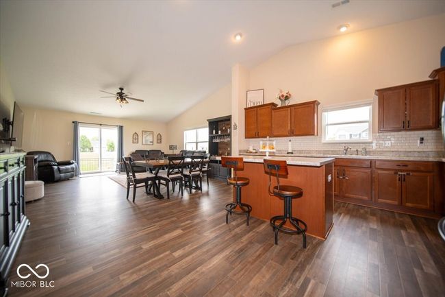 kitchen with open floor plan, brown cabinetry, ceiling fan, light countertops, and decorative backsplash | Image 8