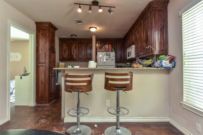 Kitchen with a kitchen bar, white appliances, track lighting, and plenty of natural light | Image 5