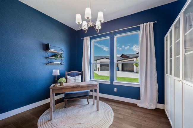 Beautiful chandelier, wood floors and 2 large windows in this private home office. | Image 18