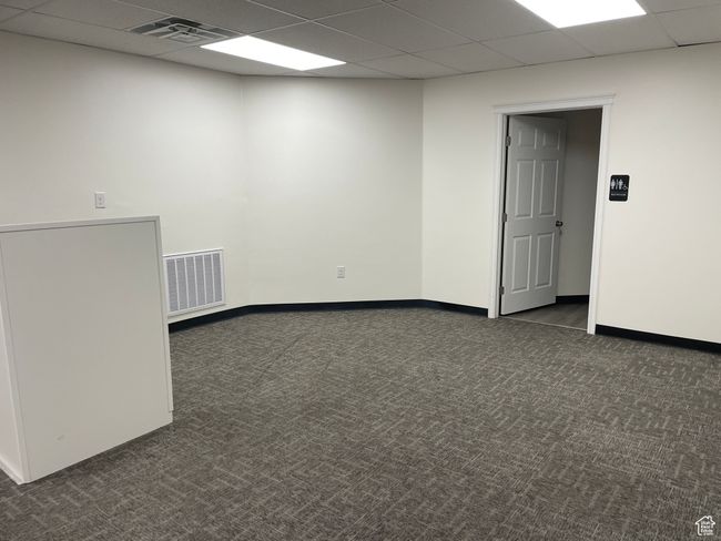 Empty room with baseboards, visible vents, a drop ceiling, and dark colored carpet | Image 9