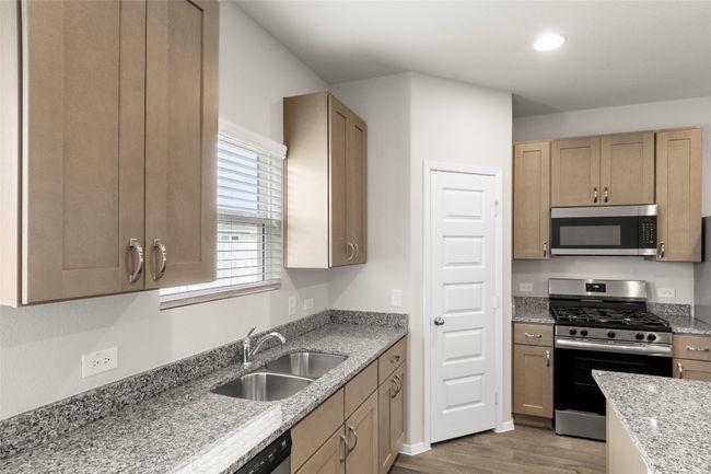 Kitchen featuring light stone countertops, recessed lighting, a sink, wood finished floors, and appliances with stainless steel finishes | Image 23