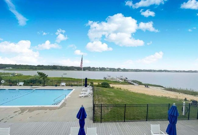 Community pool with a water view, fence, and a lawn | Image 11
