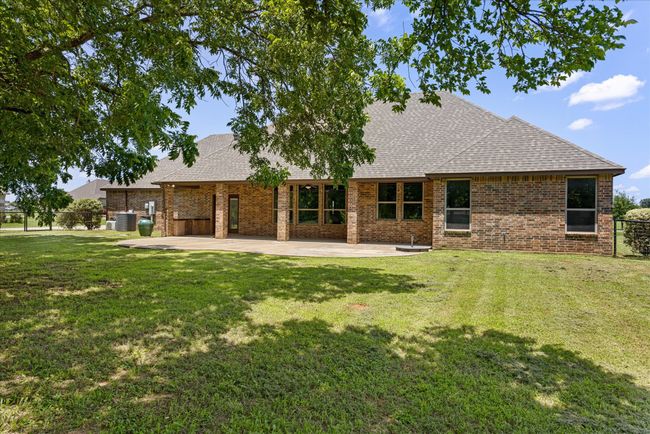 Rear view of property featuring roof with shingles, a patio area, brick siding, and a lawn | Image 33