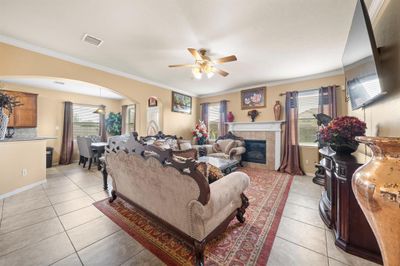 Step into this elegant living room featuring tile flooring, windows that let in ample natural light, and a cozy gas fireplace perfect for family gatherings and relaxation. | Image 3