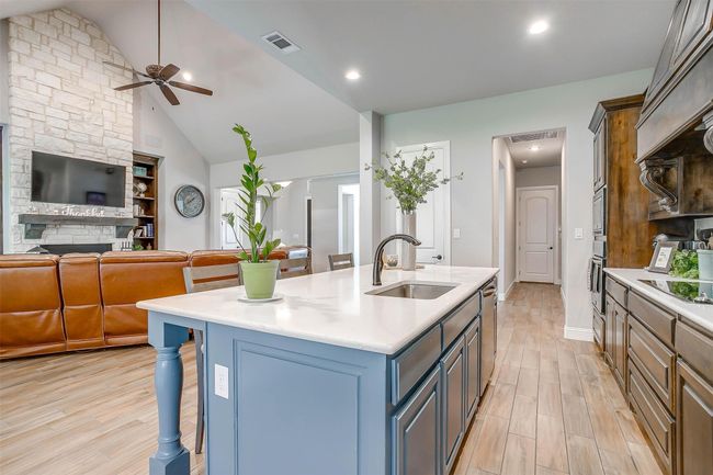 Kitchen with light wood-type flooring, custom exhaust hood, a ceiling fan, light countertops, and oven | Image 15