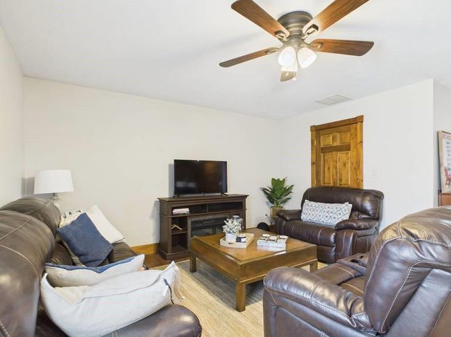 Living room featuring visible vents, baseboards, a ceiling fan, and wood floors | Image 20