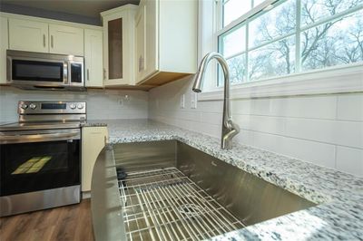 Kitchen with appliances with stainless steel finishes, light stone counters, backsplash, and dark hardwood / wood-style flooring | Image 3