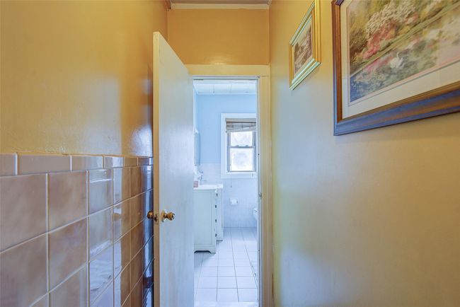 Hallway with tile walls, tile patterned flooring, wainscoting, and crown molding | Image 35