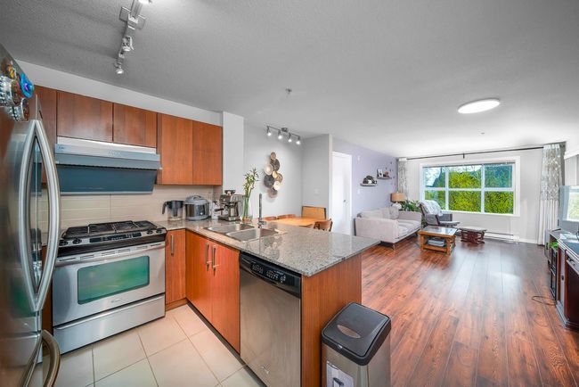 Kitchen with track lighting, open floor plan, a peninsula, under cabinet range hood, and stainless steel appliances | Image 5