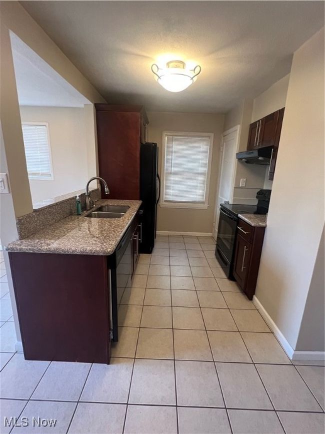 Kitchen with sink, refrigerator, light tile floors, and stove | Image 21
