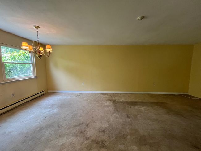 Carpeted spare room featuring a chandelier, a smoke detector, baseboards, and baseboard heating | Image 7